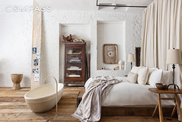 bedroom with a textured wall and wood finished floors