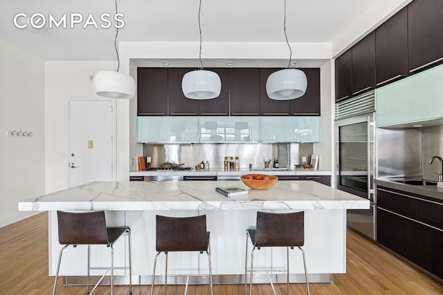 kitchen with backsplash, a kitchen island, a breakfast bar area, and decorative light fixtures