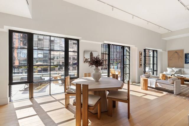 dining space with track lighting, light wood-type flooring, and a high ceiling