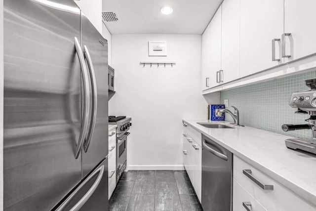 kitchen with appliances with stainless steel finishes, tasteful backsplash, white cabinets, dark hardwood / wood-style flooring, and sink