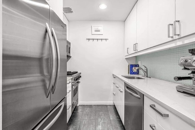 250 W 15th St Unit 1C, New York City, NY 10011 - kitchen featuring appliances with stainless steel finishes, a sink, white cabinetry, dark wood-style flooring, and baseboards