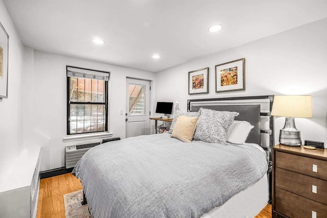 bedroom featuring light hardwood / wood-style flooring and a wall mounted AC