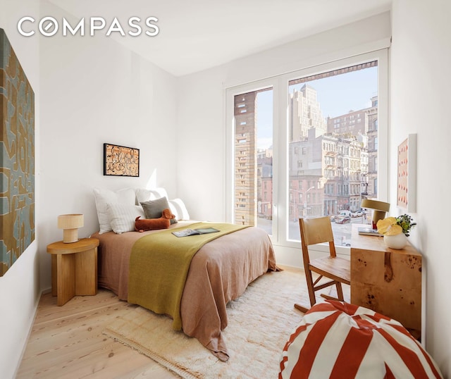 bedroom featuring a view of city, baseboards, and wood finished floors