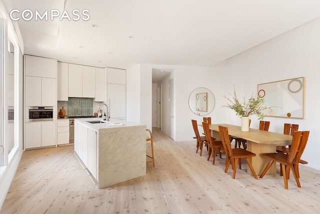 kitchen with stainless steel oven, modern cabinets, and light wood-type flooring