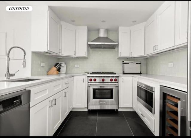 kitchen with white cabinetry, wine cooler, sink, appliances with stainless steel finishes, and wall chimney range hood