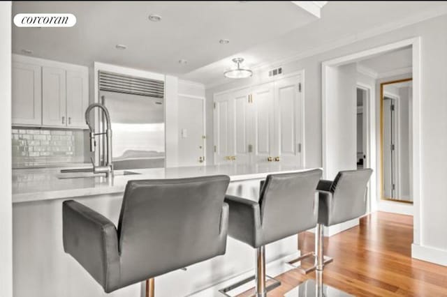 kitchen featuring kitchen peninsula, light hardwood / wood-style floors, built in fridge, crown molding, and decorative backsplash