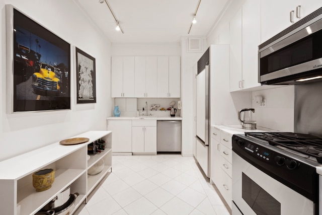 kitchen with track lighting, stainless steel appliances, light tile patterned floors, sink, and white cabinetry