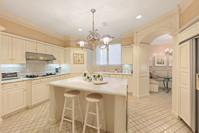 kitchen with pendant lighting, light countertops, gas stovetop, and under cabinet range hood