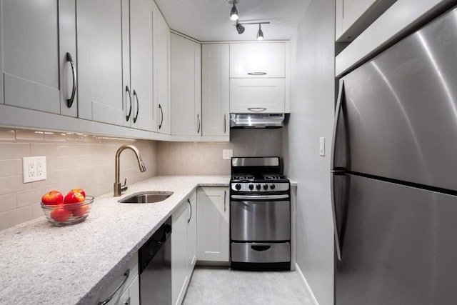 kitchen featuring stainless steel appliances, light stone countertops, backsplash, sink, and white cabinetry