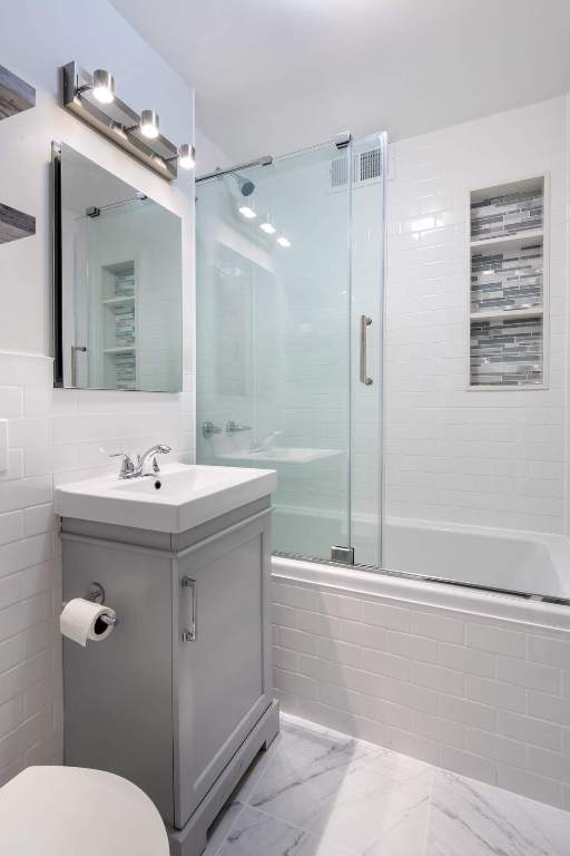 full bathroom featuring combined bath / shower with glass door, vanity, and toilet