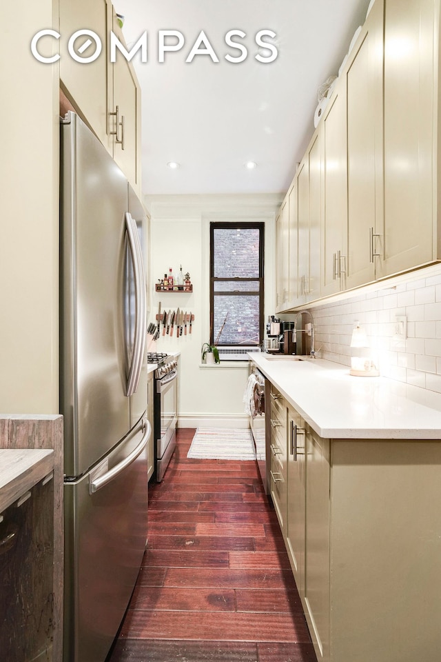 kitchen with backsplash, dark wood-type flooring, light countertops, appliances with stainless steel finishes, and a sink