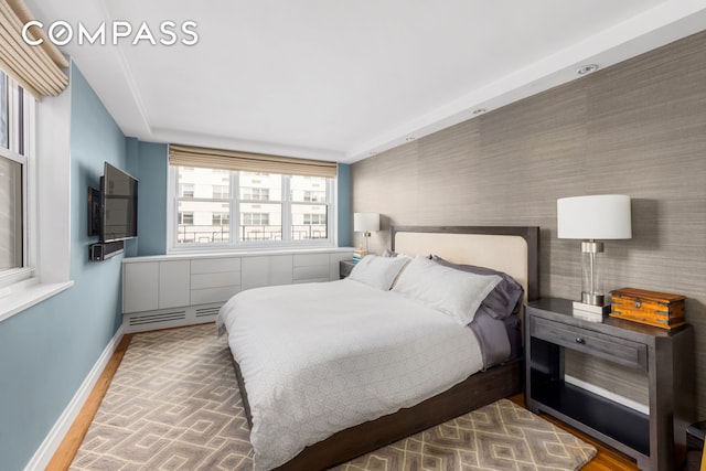 63 E 9th St Unit 14K, New York City, NY 10003 - bedroom with baseboards, a baseboard radiator, and wood finished floors