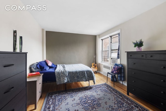 bedroom with hardwood / wood-style flooring and radiator heating unit