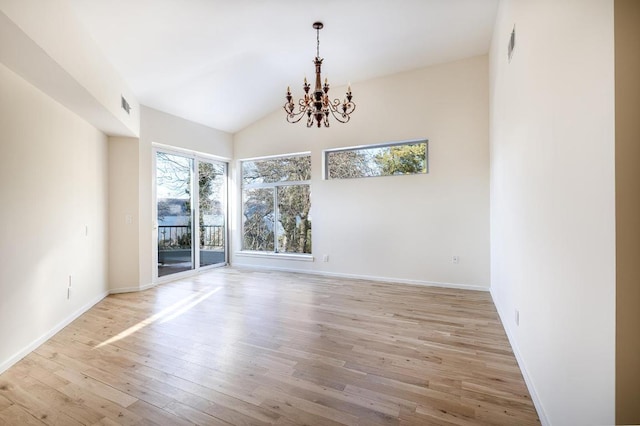 empty room featuring lofted ceiling, a chandelier, and light hardwood / wood-style floors