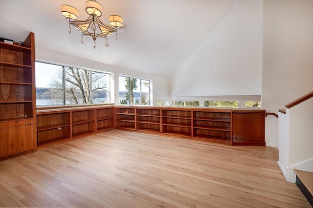 unfurnished room with high vaulted ceiling, light wood-type flooring, and an inviting chandelier