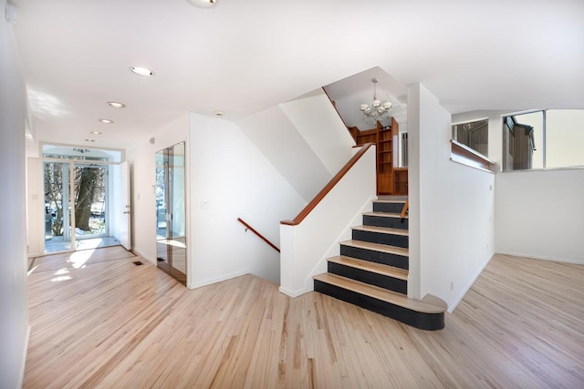 stairway with an inviting chandelier and wood-type flooring