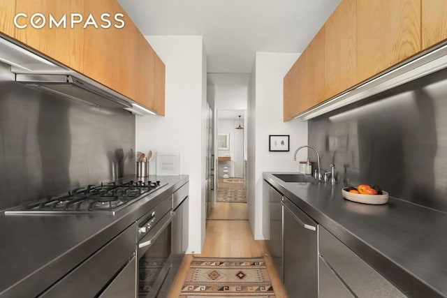 kitchen with appliances with stainless steel finishes, sink, extractor fan, and light wood-type flooring