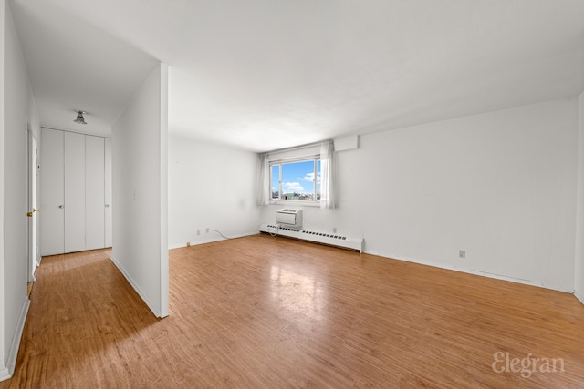 empty room with baseboard heating, baseboards, and wood finished floors