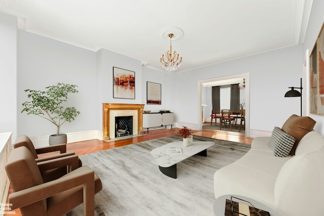 living area featuring baseboards, a fireplace with flush hearth, a chandelier, and crown molding