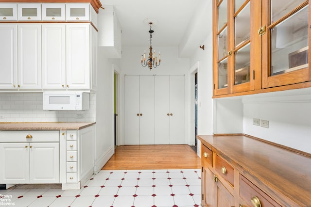 310 W 86th St Unit 3A, New York City, NY 10024 - kitchen with a chandelier, white microwave, decorative light fixtures, and white cabinets