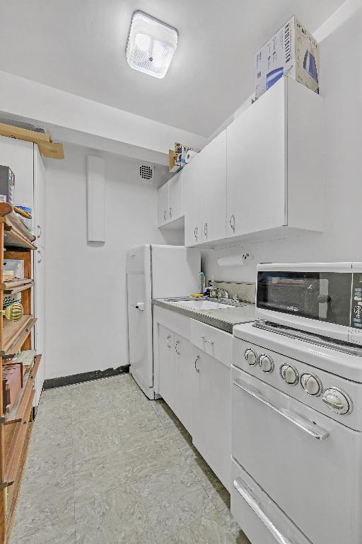 kitchen with sink, white appliances, and white cabinets