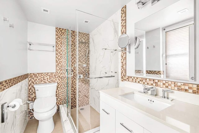 bathroom with a shower with shower door, a wealth of natural light, toilet, tile walls, and vanity