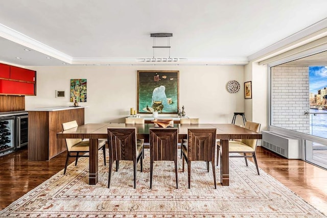 dining room featuring wood finished floors, ornamental molding, radiator, bar area, and wine cooler