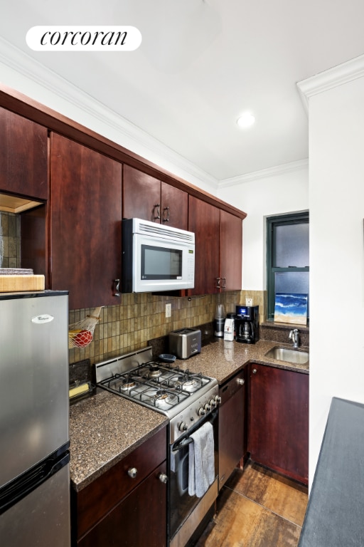 kitchen featuring appliances with stainless steel finishes, dark wood-type flooring, decorative backsplash, crown molding, and sink