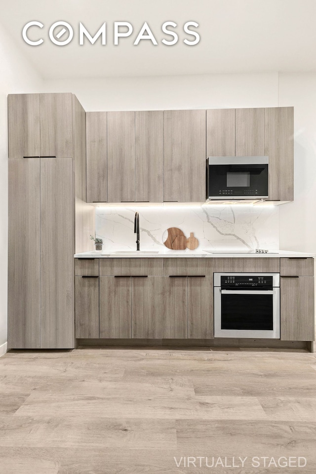 kitchen with light countertops, oven, a sink, and modern cabinets