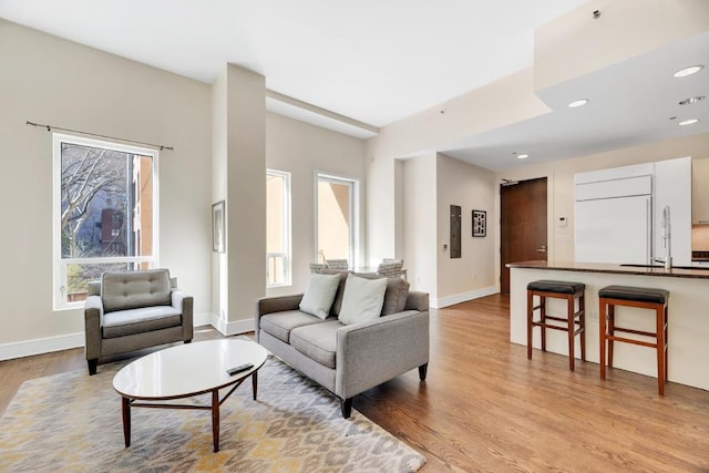 living room featuring light wood-style flooring, baseboards, and recessed lighting