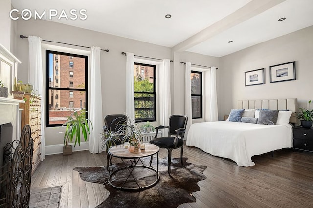 bedroom with recessed lighting, dark wood-style flooring, and a fireplace