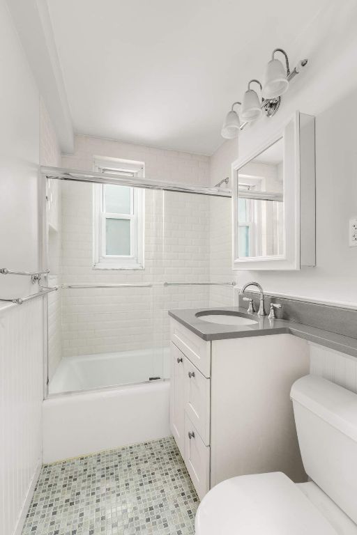 full bathroom with vanity, bath / shower combo with glass door, and toilet