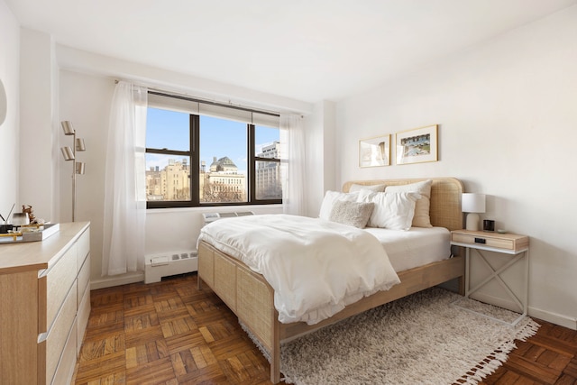 bedroom featuring baseboards, a baseboard radiator, and a city view