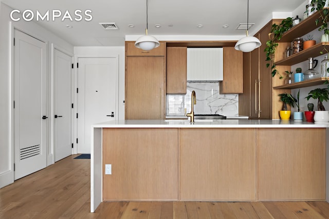 kitchen with open shelves, light countertops, wood-type flooring, tasteful backsplash, and pendant lighting