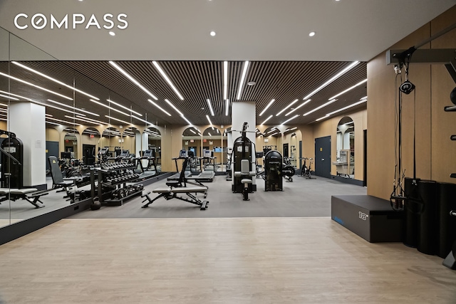 gym featuring arched walkways and wood finished floors