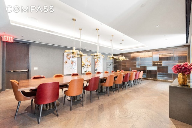 dining space with light parquet flooring and a raised ceiling