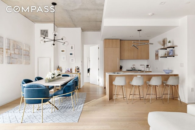 kitchen with a chandelier, a kitchen breakfast bar, light hardwood / wood-style floors, kitchen peninsula, and hanging light fixtures