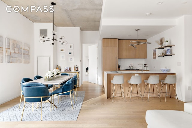 kitchen with light wood-style flooring, a breakfast bar area, modern cabinets, and visible vents