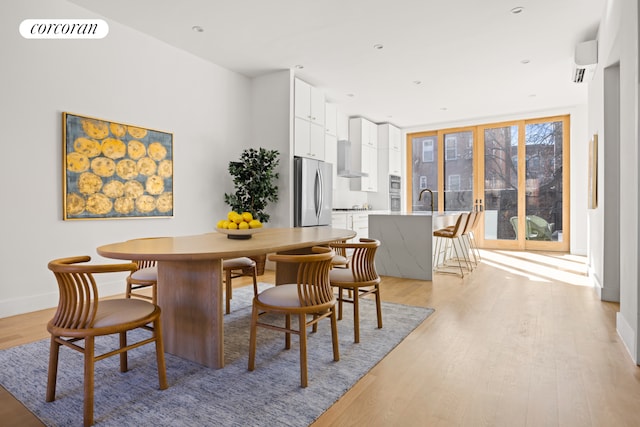 dining room with baseboards, visible vents, a wall unit AC, and light wood-type flooring