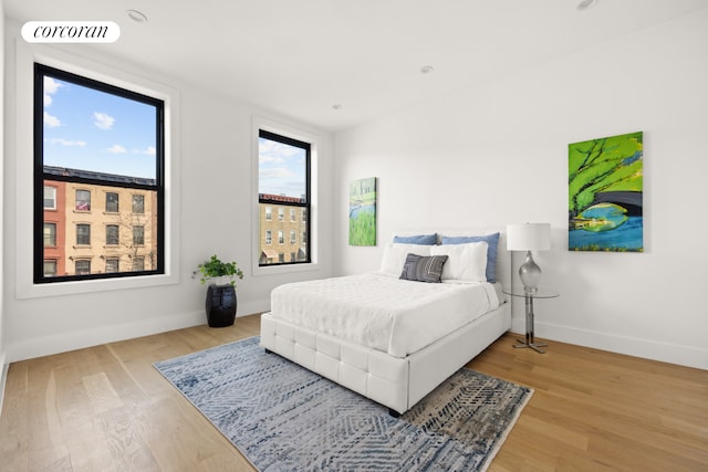 bedroom with baseboards, visible vents, and wood finished floors