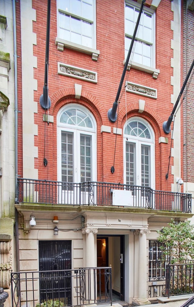 property entrance featuring french doors, brick siding, and a balcony