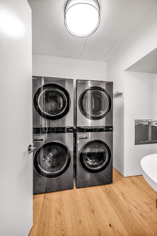 washroom with laundry area, wood finished floors, and stacked washer and clothes dryer