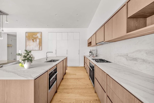 kitchen with wall oven, a kitchen island with sink, a sink, and open shelves