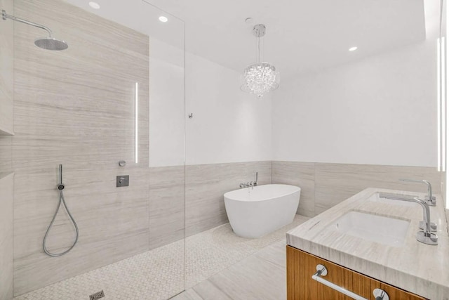 full bath featuring a freestanding tub, a sink, tile walls, double vanity, and walk in shower