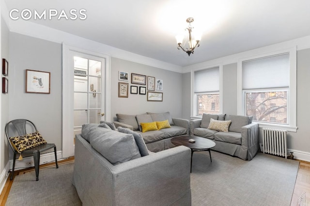 living area with radiator, baseboards, a chandelier, and wood finished floors