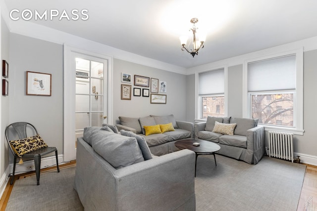 living area featuring a chandelier, parquet floors, baseboards, and radiator heating unit