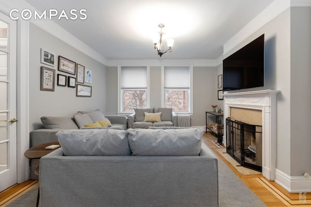 living room with a fireplace, light hardwood / wood-style flooring, a notable chandelier, and radiator heating unit