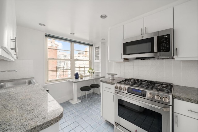 kitchen featuring white cabinets, light tile patterned floors, stainless steel appliances, and sink