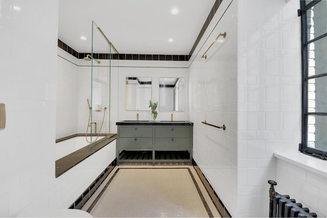 bathroom featuring tile walls, radiator, vanity, and shower / bathtub combination