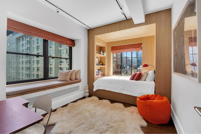 322 E 57th St Unit 12A, New York City, NY 10022 - bedroom featuring baseboards, rail lighting, wood finished floors, and wooden walls